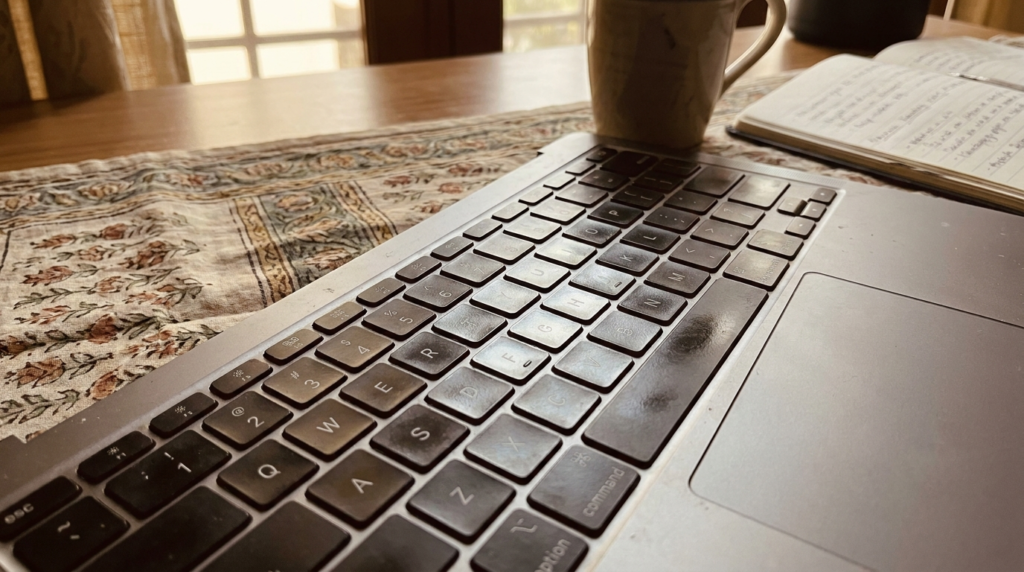 A close-up shot of a laptop's keyboard, highlighting the keys and a portion of the trackpad, with soft ambient lighting to suggest a workspace.